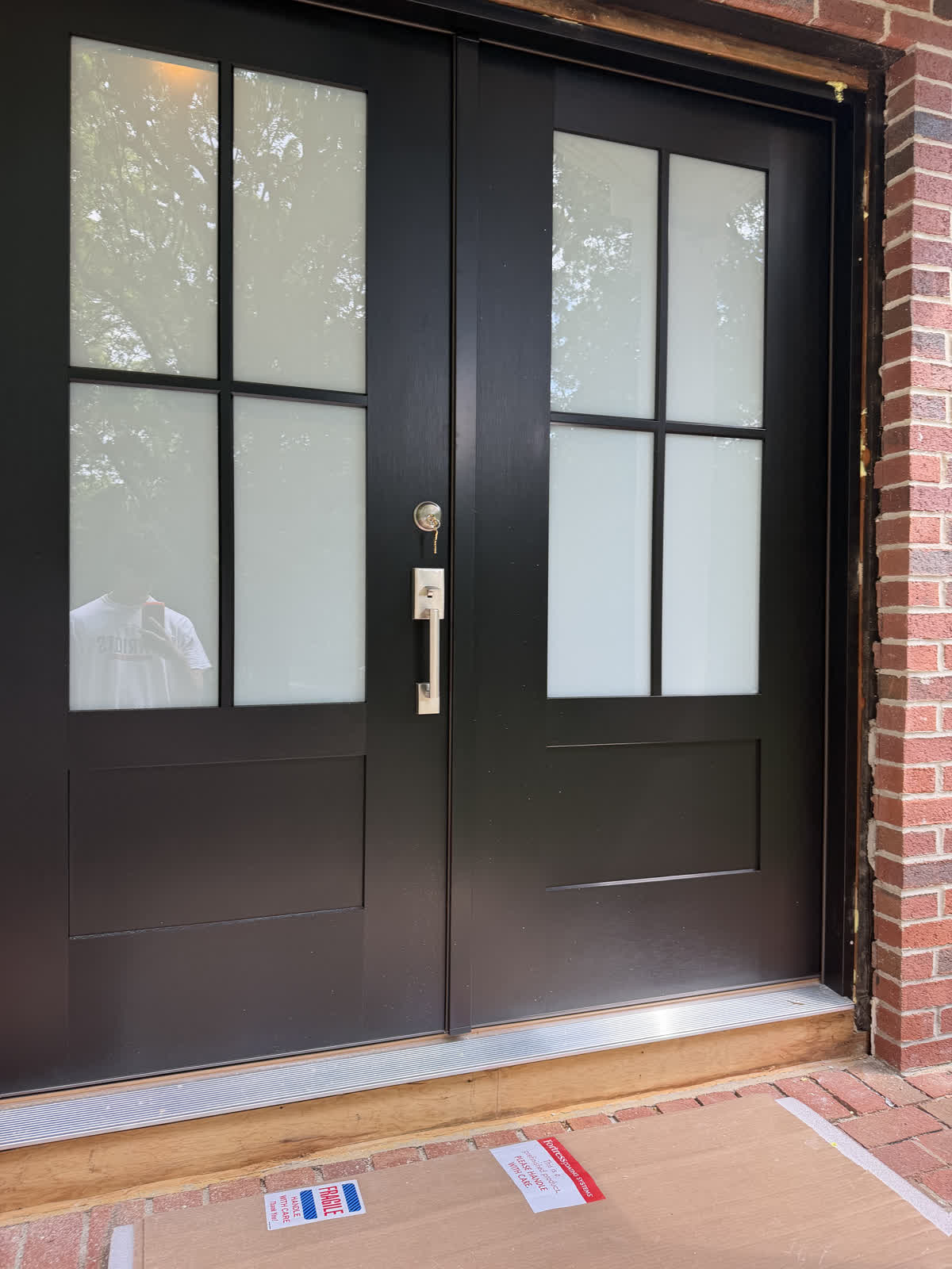 Double French-style front door installation on a brick entryway